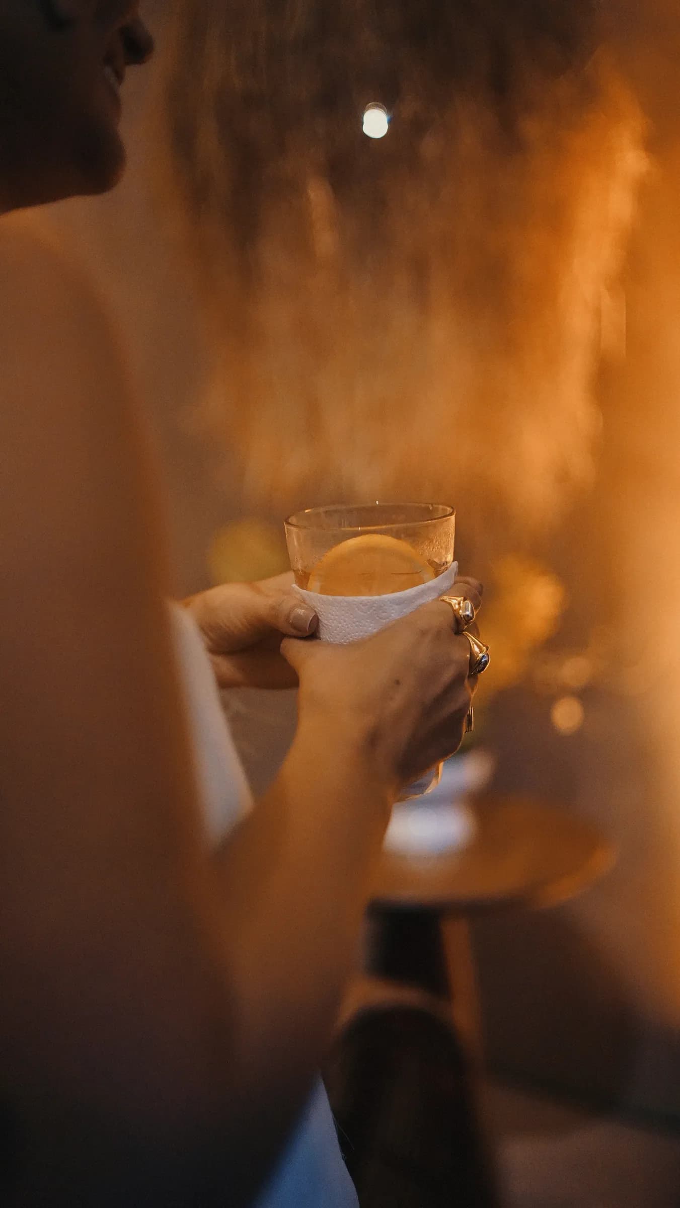 Convidada segurando copo de drink, retrato contra a luz dourada