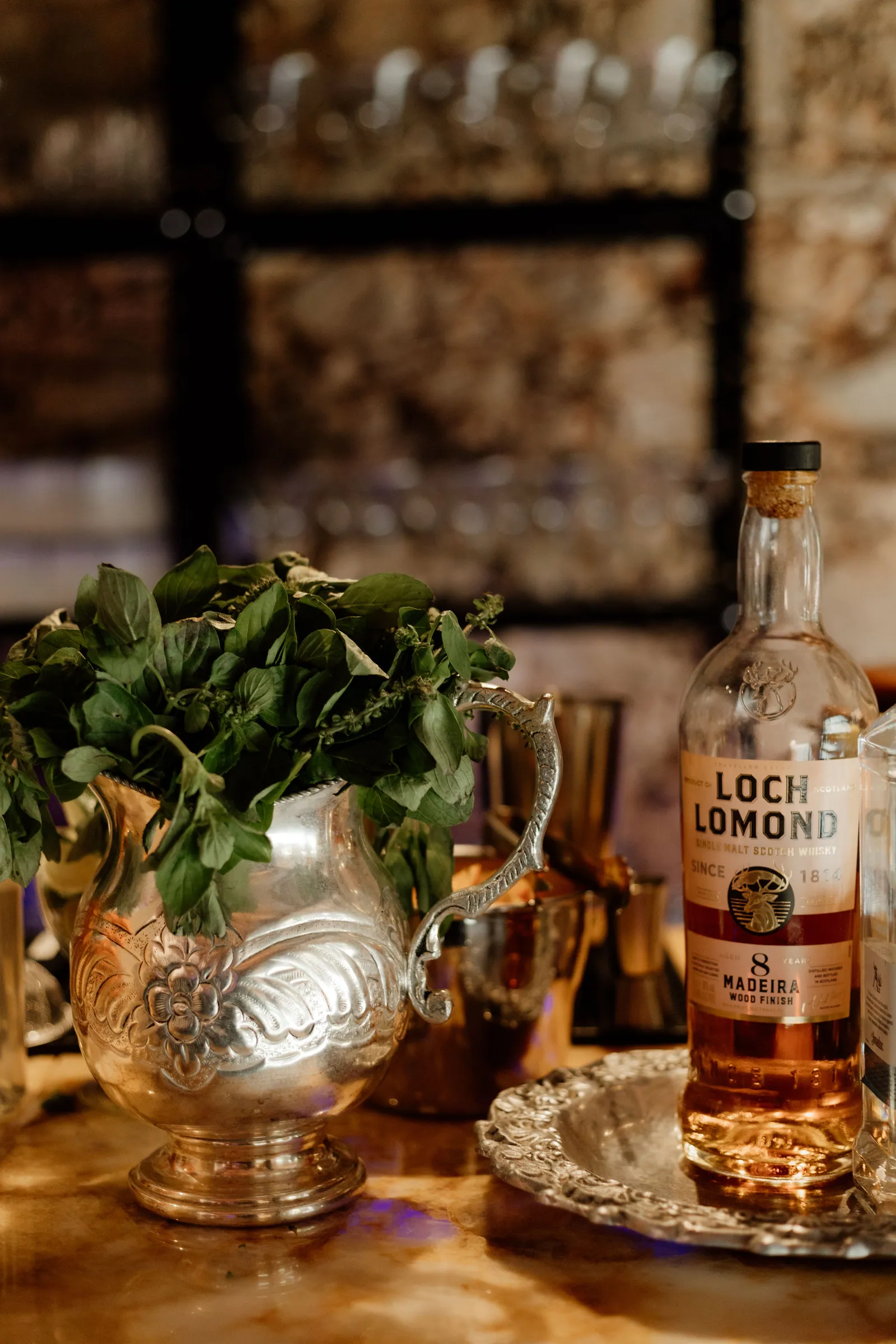 Hortelã fresca dentro de jarra de prata, ao lado de garrafa de whisky