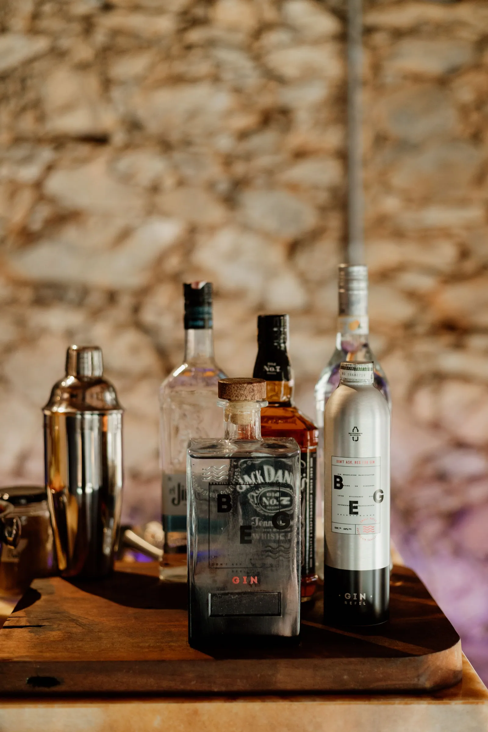 Shaker de coquetel, whisky e outras garrafas sobre tábua de madeira