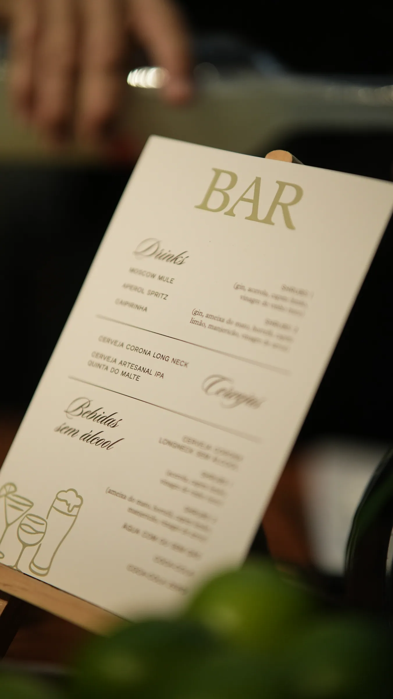 Cardápio "Bar" apoiado sobre a mesa, entre folhagens