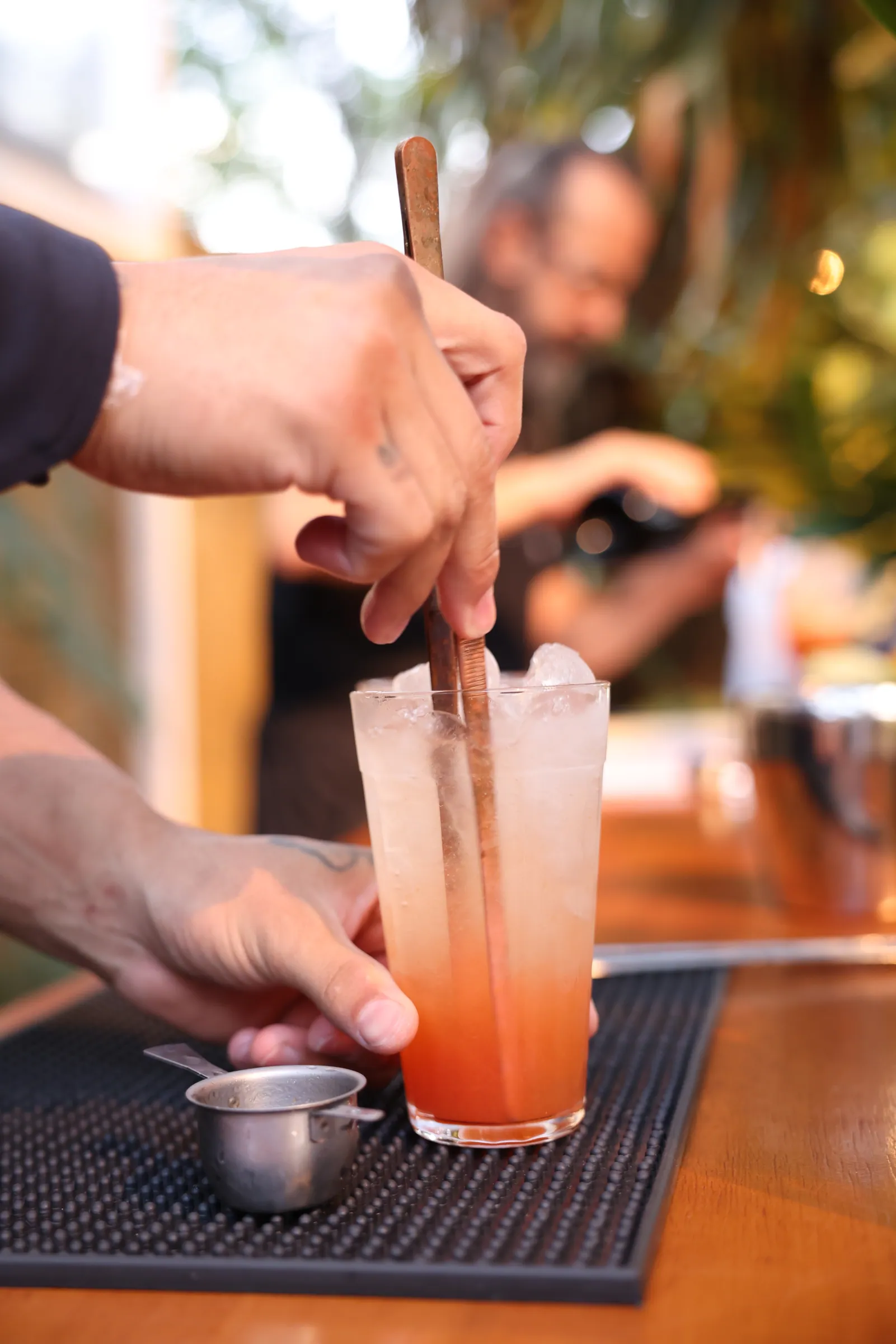 Bartender mexendo drink com colher longa em copo, ao ar livre