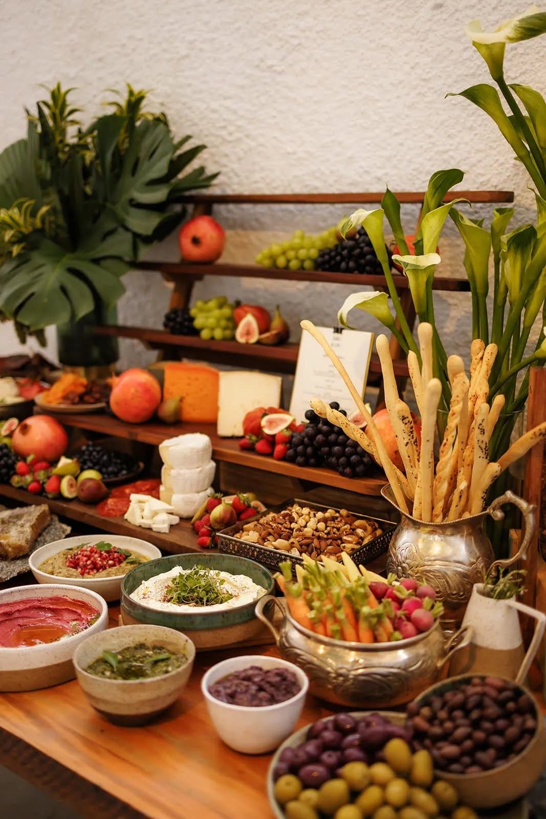 Mesa de antepastos e charcuterie com pães frutas queijos e copos de leite na Casa Cósmica SP