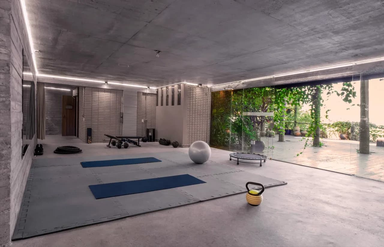 Espaço de treino da Residência Cósmica com tapetes, kettlebell e vista aberta para o jardim