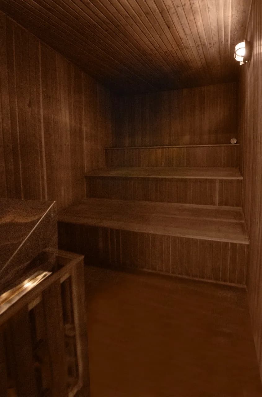 Sauna de madeira da Residência Cósmica, bancos escalonados sob luz baixa