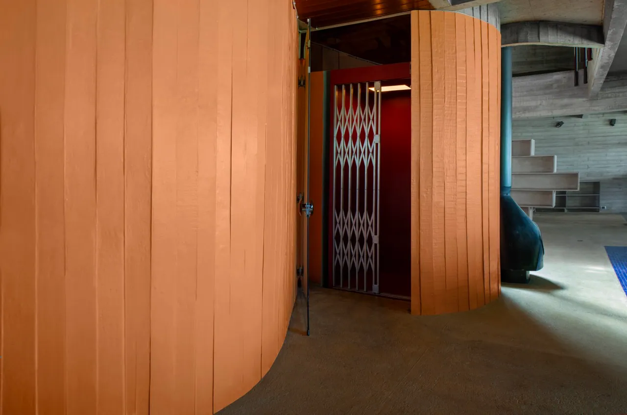 Torre curva laranja com elevador de grade antiga e interior vermelho