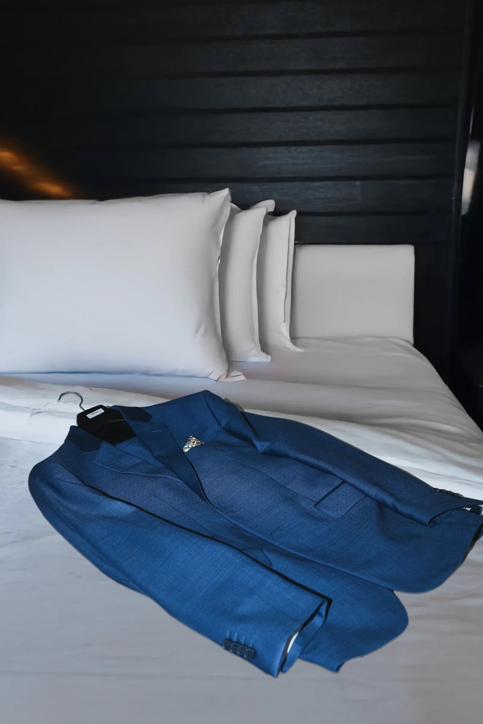 Terno azul do noivo sobre cama branca na hospedagem da Fazenda Cósmica para casamento intimista