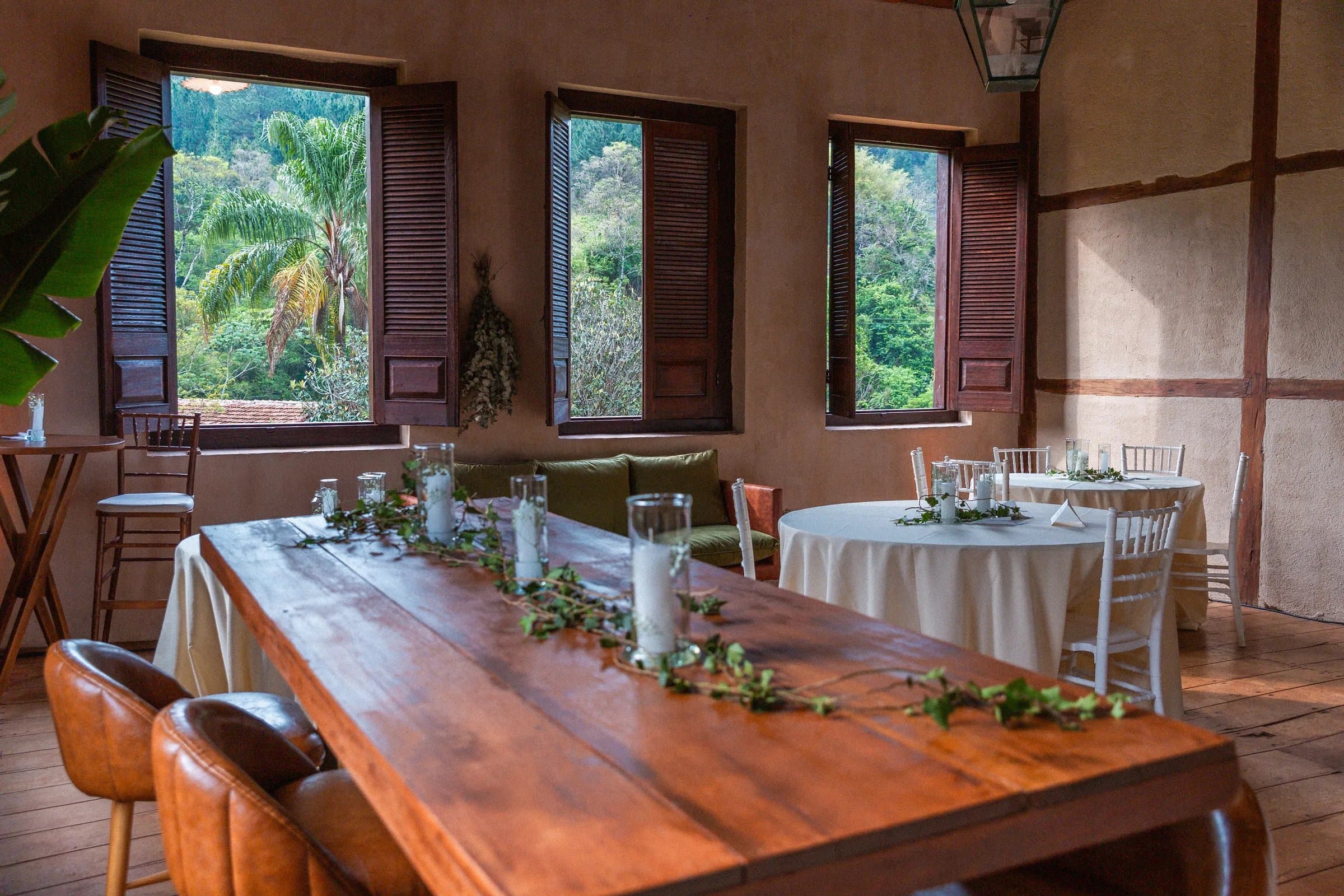 Mesa de madeira posta com hera e velas em ambiente rústico da Fazenda Cósmica para casamento