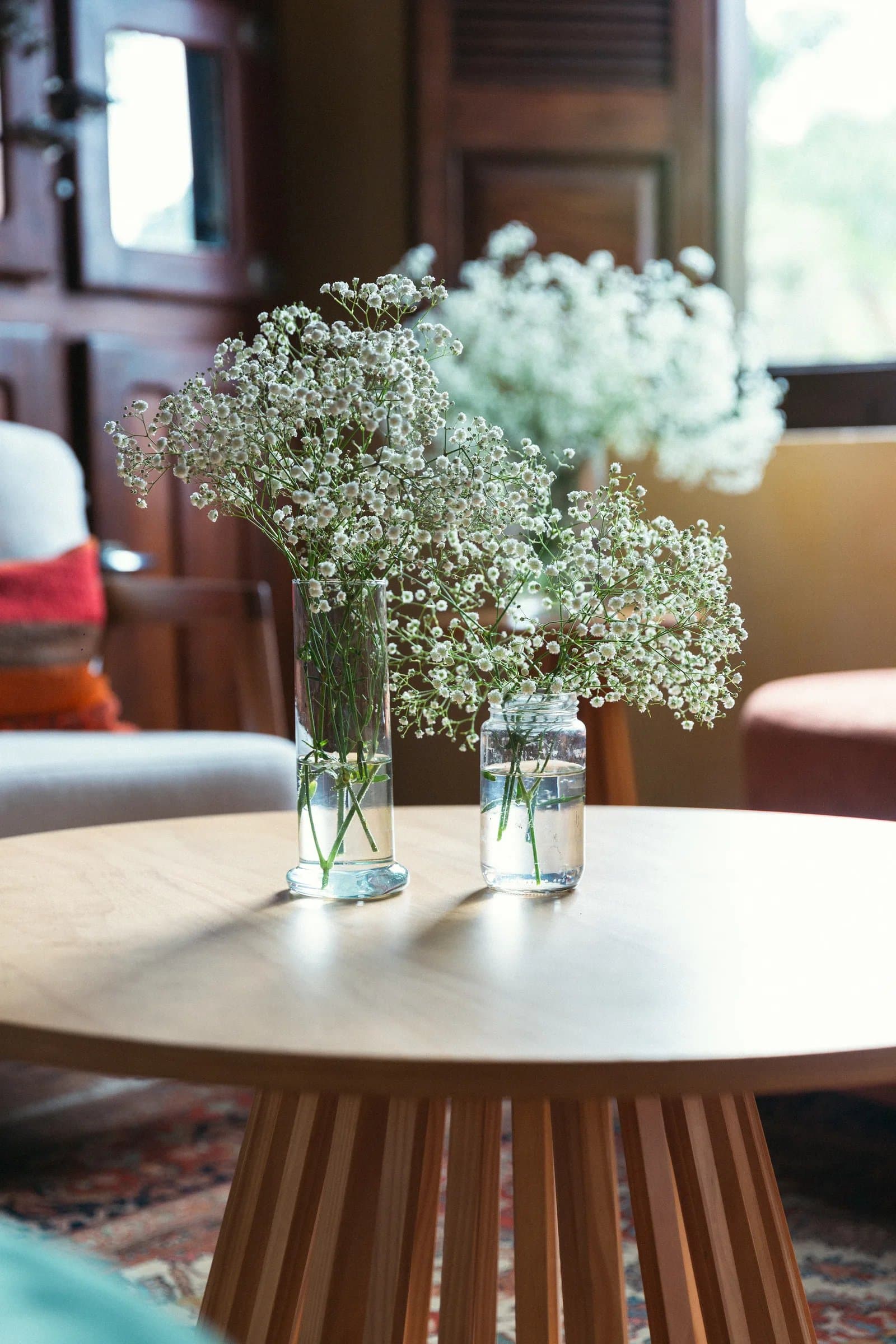 Vasos de mosquitinho em mesa de madeira na decoração floral do casamento na Fazenda Cósmica