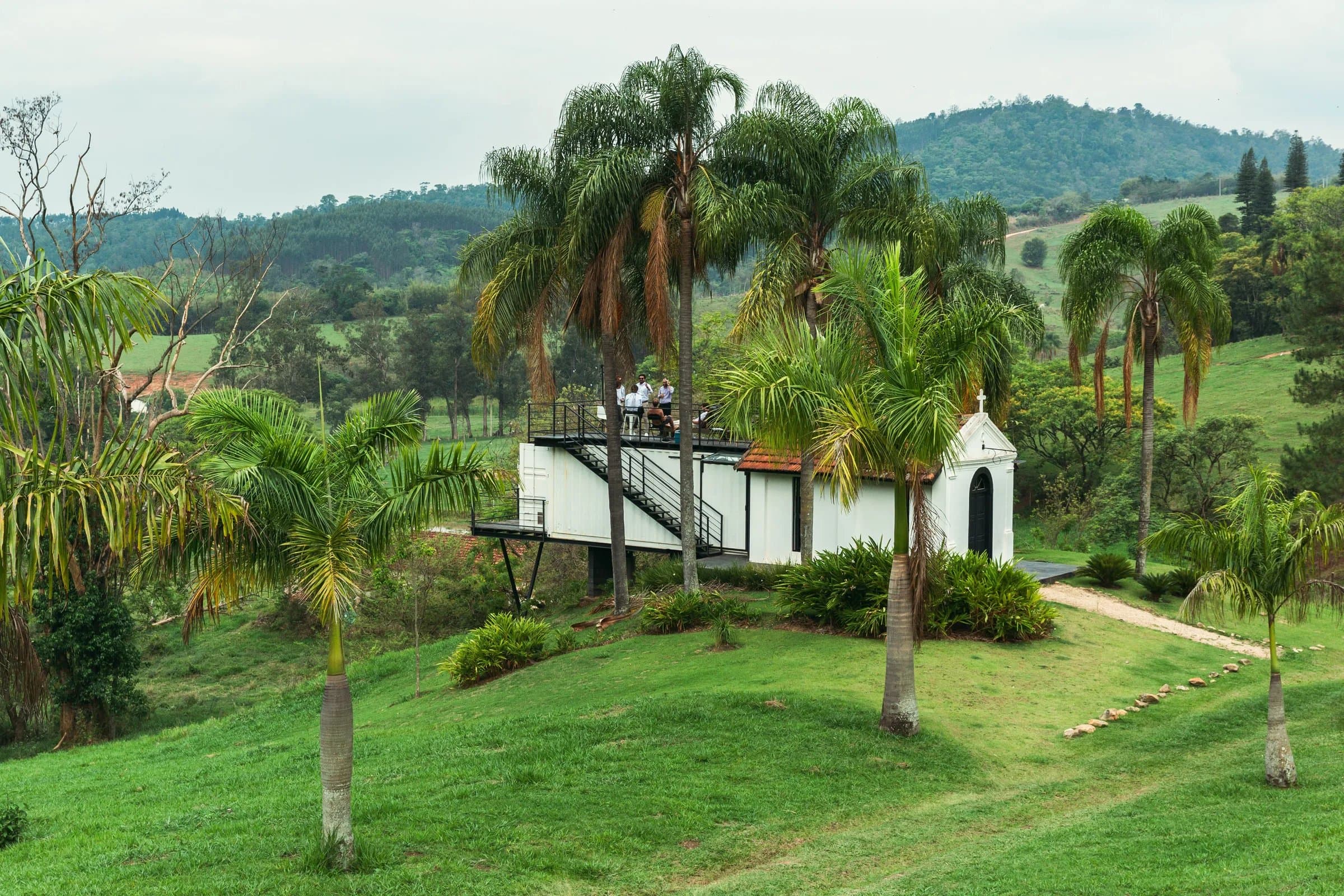 Capela branca em meio à mata com vista para as montanhas na Fazenda Cósmica em Amparo SP
