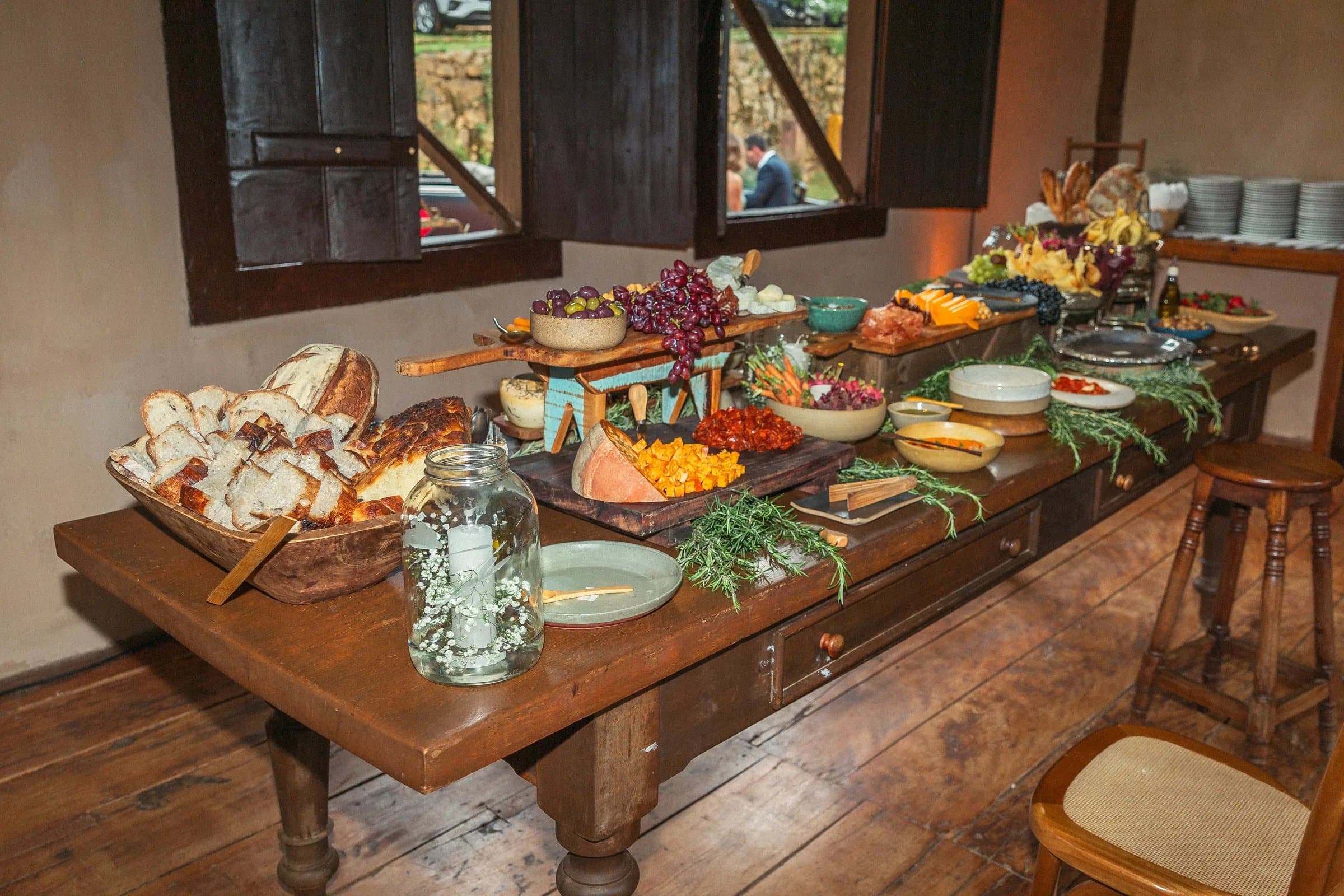 Mesa com gastronomia autoral pães queijos frutas e antepastos no casamento na Fazenda Cósmica