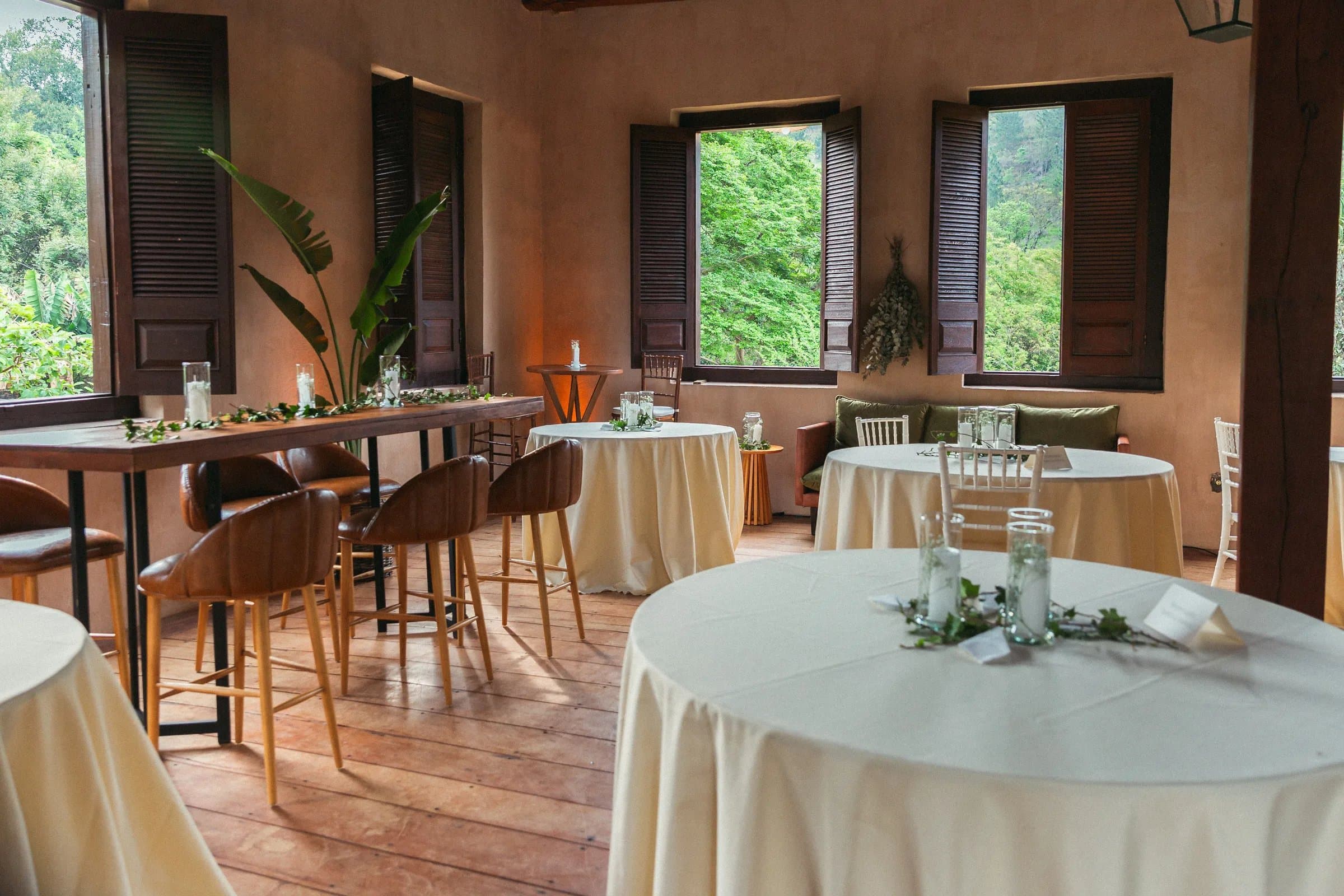 Salão com mesas redondas e bistrô preparado para recepção de casamento na Fazenda Cósmica