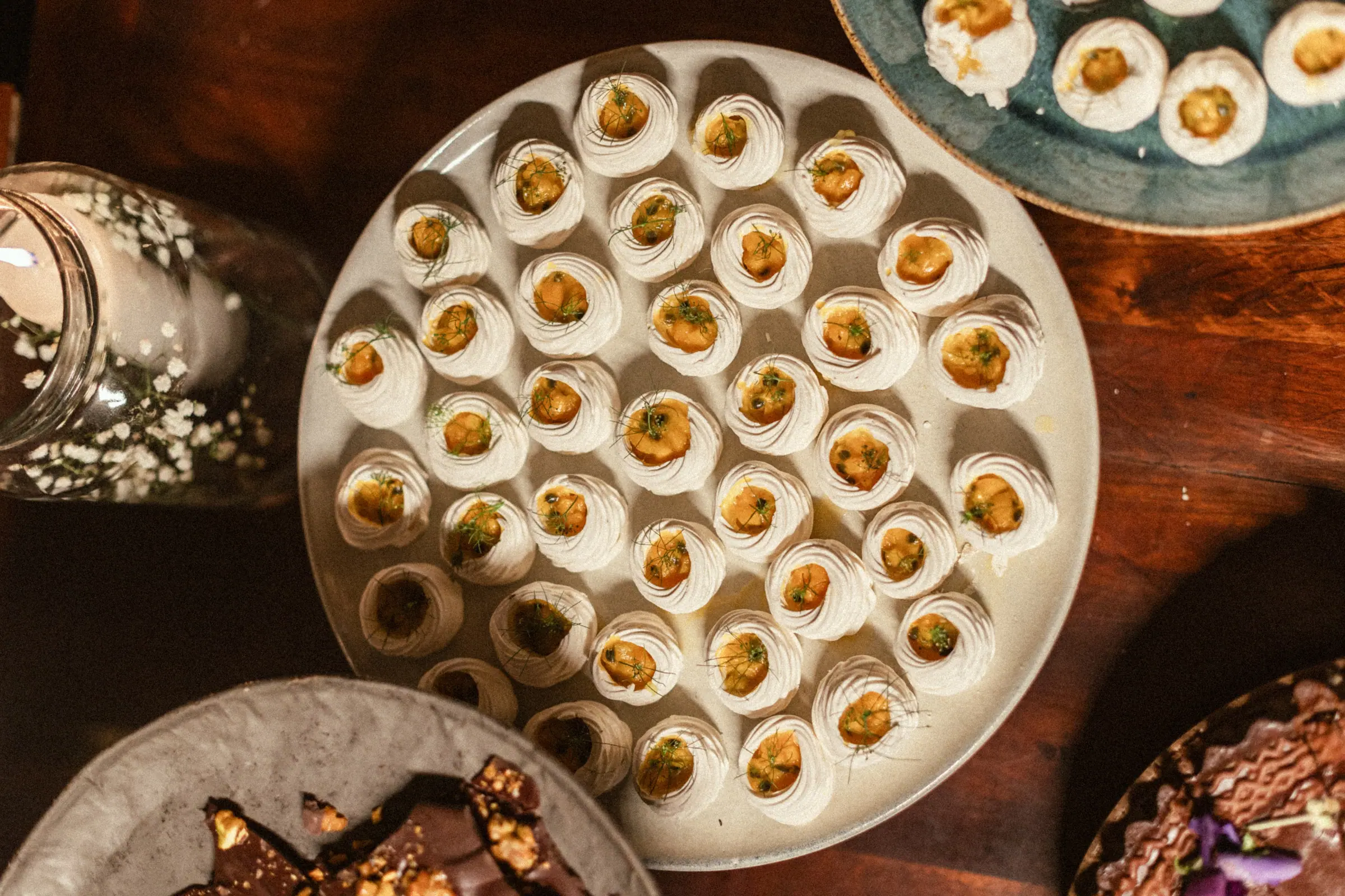 Bandeja de docinhos de merengue com recheio de doce de leite, servida entre outros pratos da festa