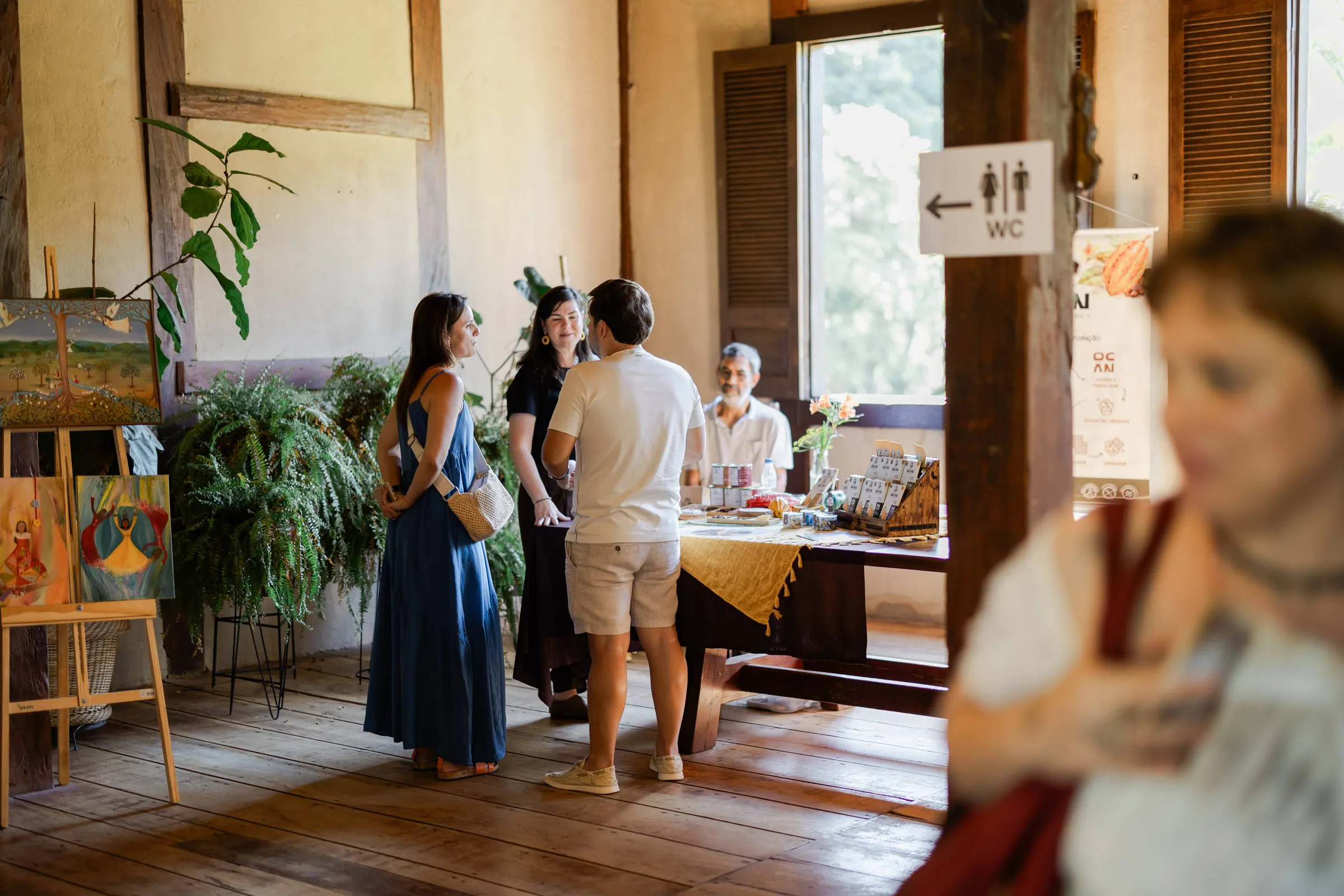 Participantes de pé conversando em sala de parede amarela da Fazenda Cósmica, em pausa de encontro corporativo