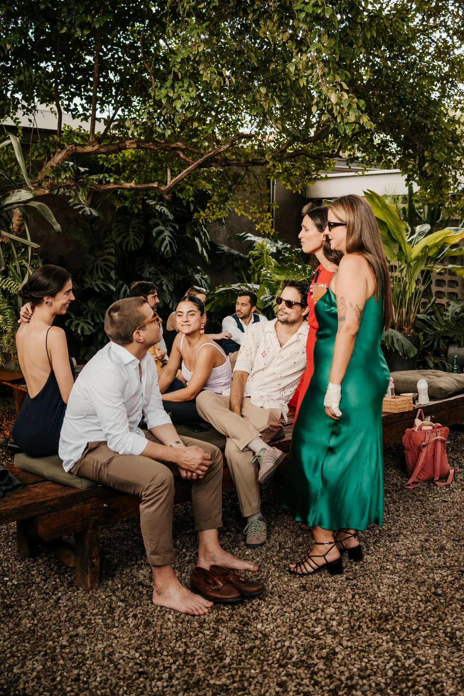 Convidados em banco rústico no jardim com folhagens tropicais na Casa Cósmica SP em São Paulo