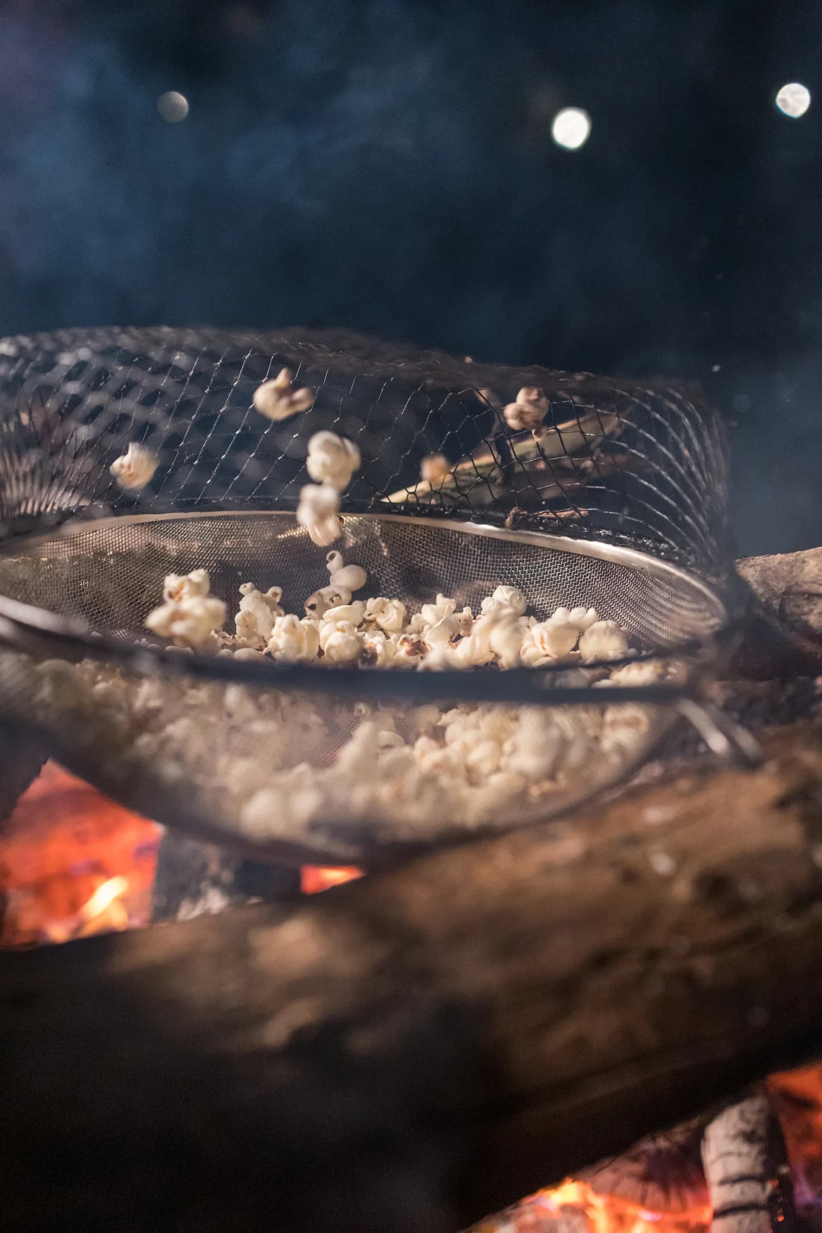 Pipoca estourando na peneira sobre o fogo, em festa na Fazenda Cósmica