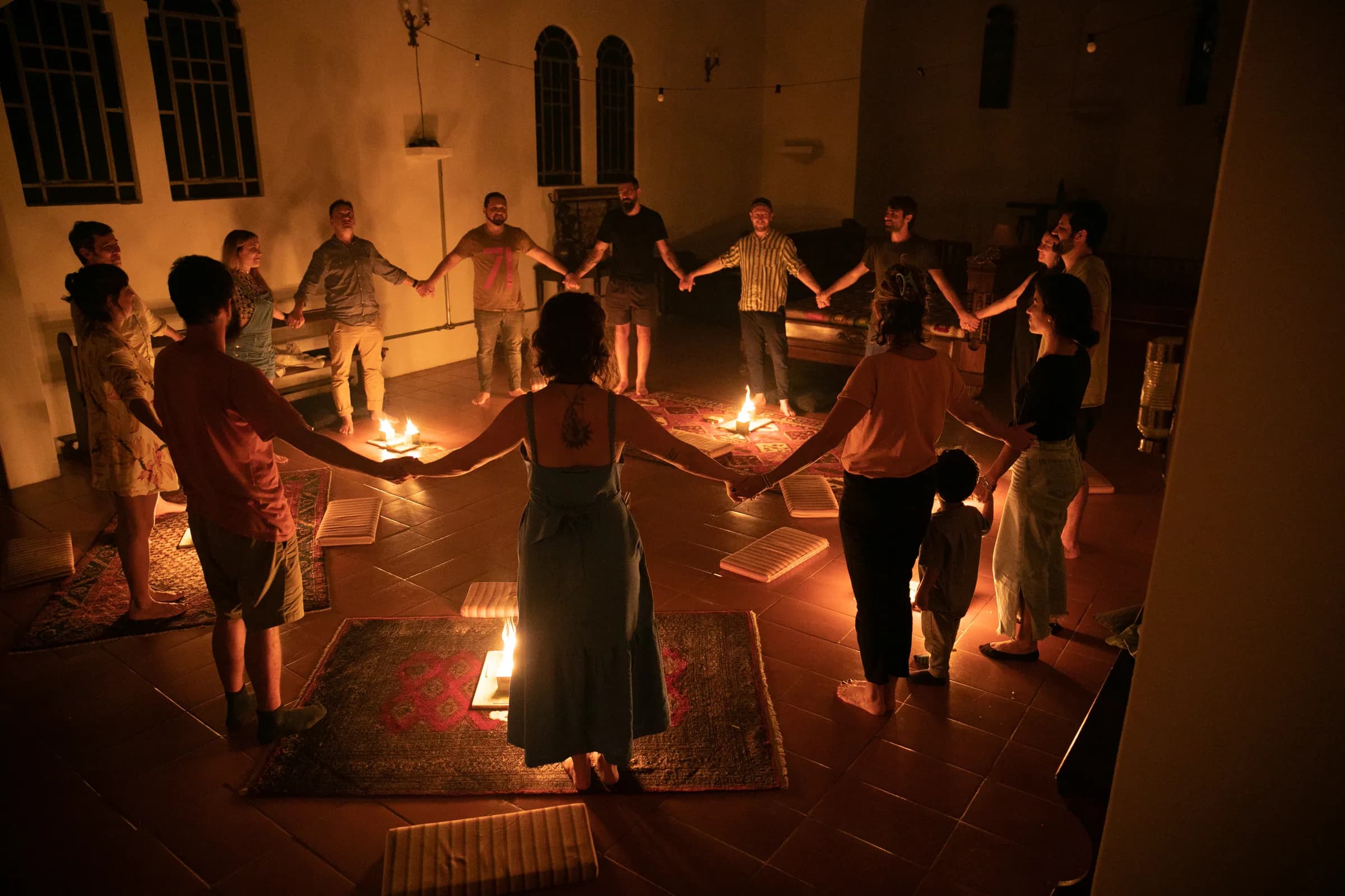 Roda de pessoas de mãos dadas à luz de velas — comunidade e presença num encontro do Clube Cósmica